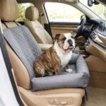 Bouledogue au pelage bringé assis dans un siège-nid gris matelassé sur le siège avant d'une voiture