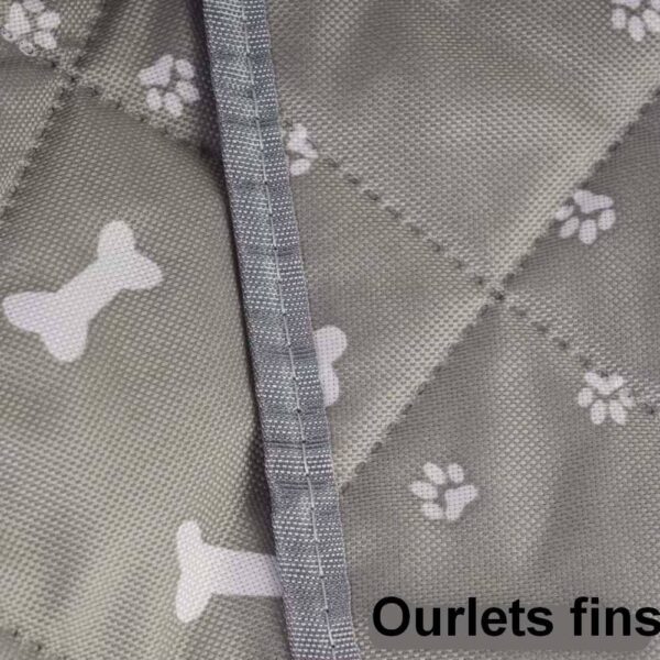 Gros plan sur un tissu gris matelassé imprimé d'os et de pattes avec couture de bordure