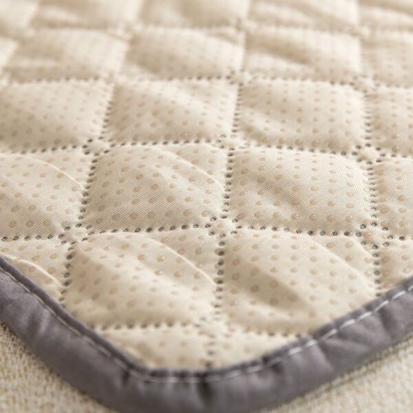 Détail du tissu matelassé beige à picots antidérapants avec bordure grise