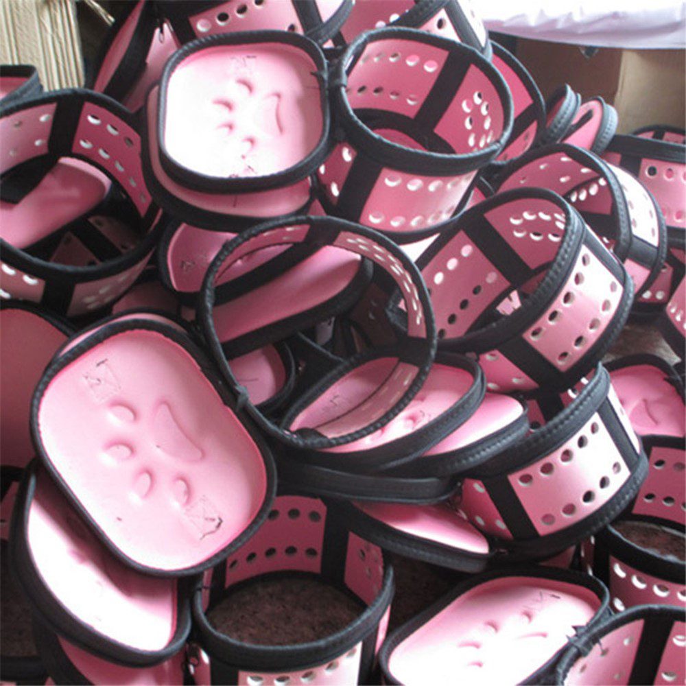 Tas de coques roses perforées à liseré noir empilées en vrac dans un entrepôt avant assemblage