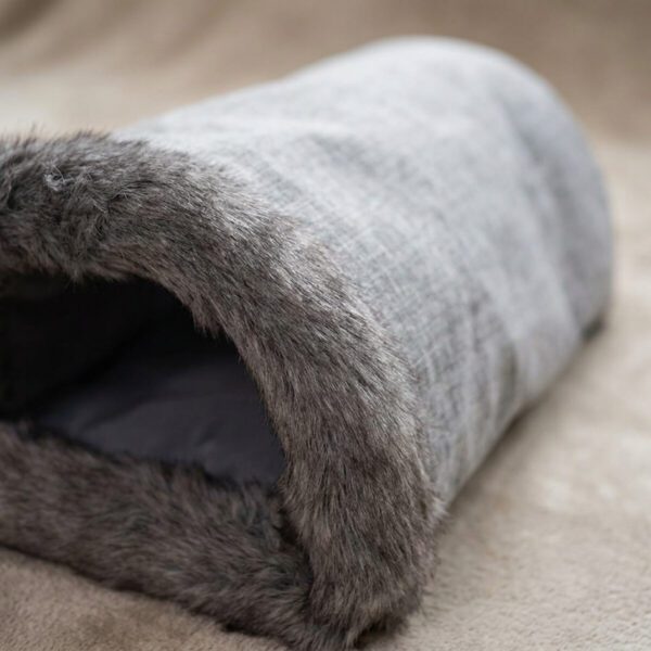 Détail de l'ouverture bordée de fourrure et du tissu gris du sac de couchage pour chat
