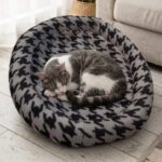 Chat gris et blanc couché dans la corbeille fourrure pour chat à motif pied-de-poule