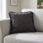 Coussin carré anthracite à bord en peluche posé dans l'angle d'un canapé