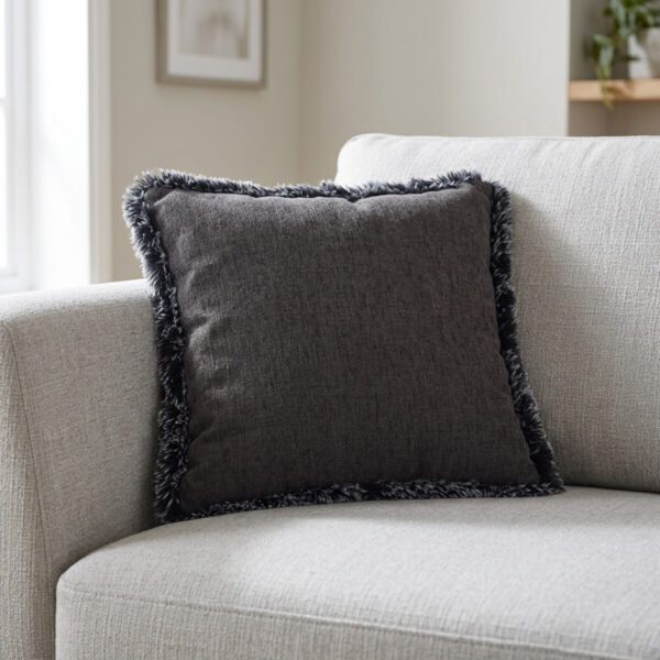Coussin carré anthracite à bord en peluche posé dans l'angle d'un canapé