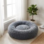 Lit rond donut gris en peluche près d'une fenêtre dans un salon