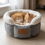 Chat roux et blanc endormi dans le panier rond gris pour chat avec bord en peluche blanche