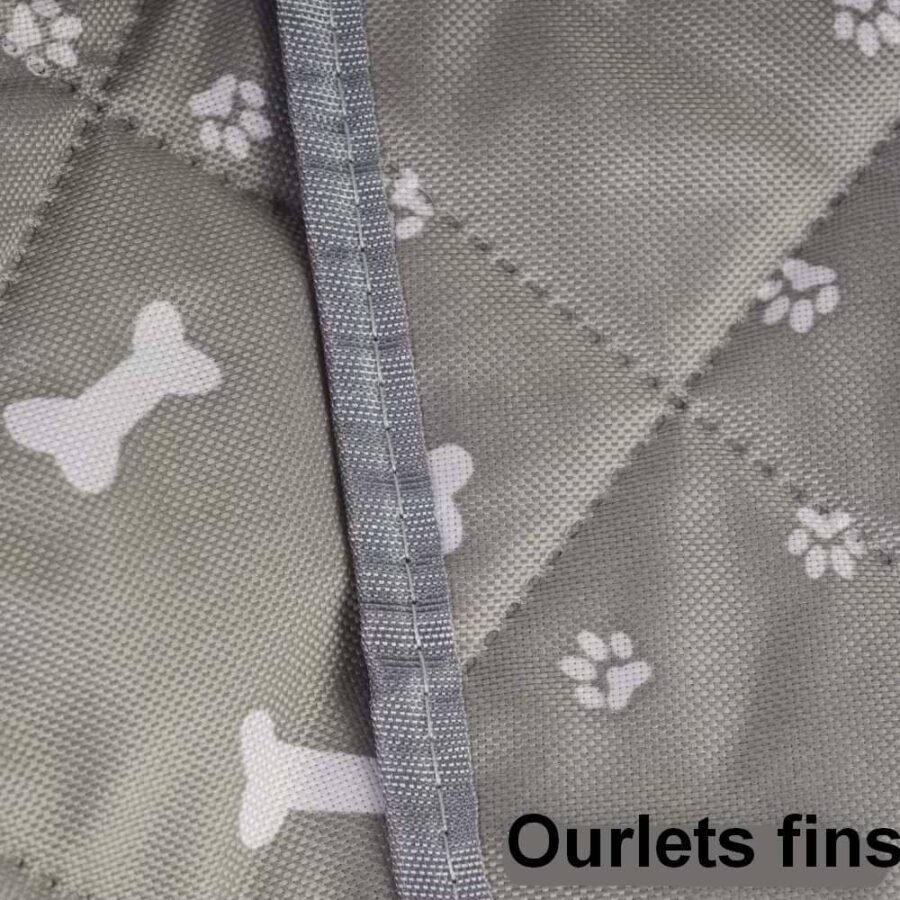 Gros plan sur un tissu gris matelassé imprimé d'os et de pattes avec couture de bordure