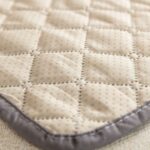 Détail du tissu matelassé beige à picots antidérapants avec bordure grise