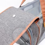 Gros plan du rabat gris chiné à bordure marron et bouton métallique, avec parois transparentes du sac de chat